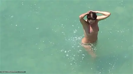 Il ragazzo si sta impantando dietro le coppie nude che fanno il bagno nel mare