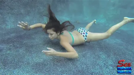 Una ragazza snella cerca di succhiare un cazzo di gomma sott'acqua