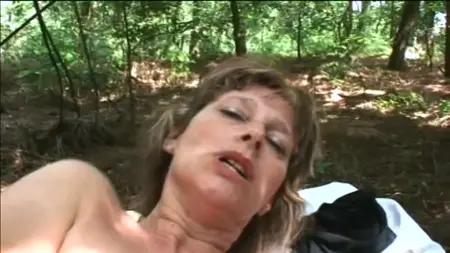 Una donna matura nella foresta mostra il suo fascino e cazzo con un uomo